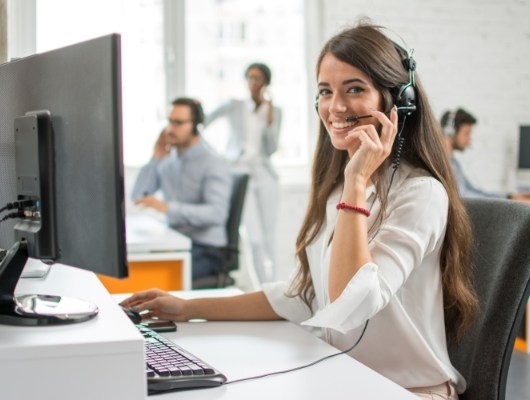 Smiling woman with headset sitting at desk with computer