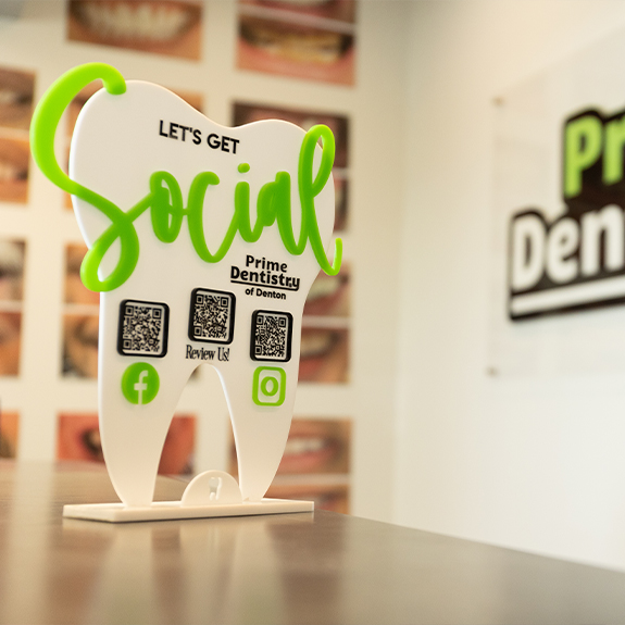 Tooth shaped stand on table with Q R codes for Prime Dentistry social media accounts