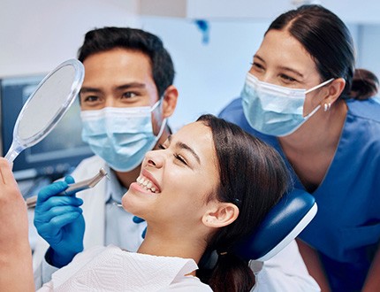 Dentist, dental assistant, and patient smiling at results