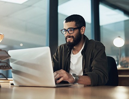 Man smiling while working on laptop in office