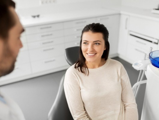 Woman in white sweater smiling at her dentist