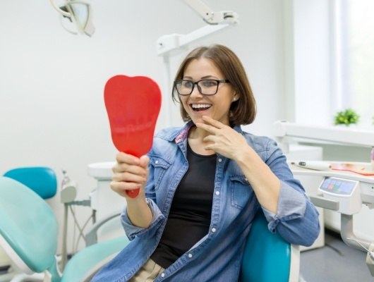 Dental patient admiring her smile in red mirror
