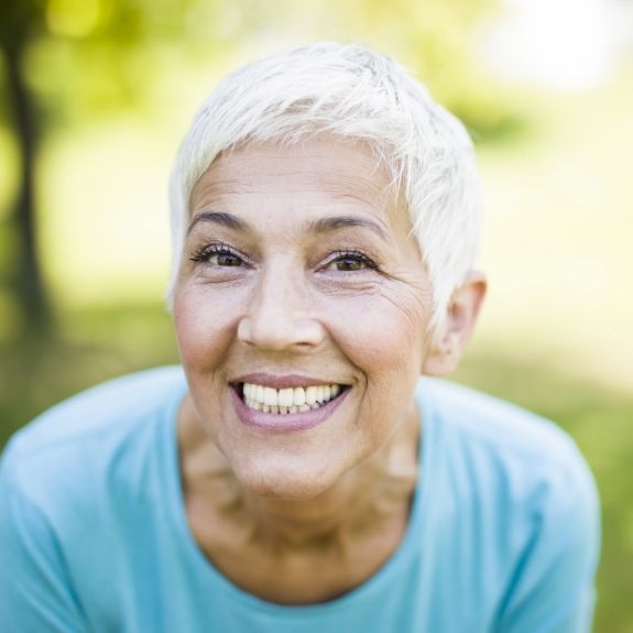 Senior woman grinning with dental crowns in Denton