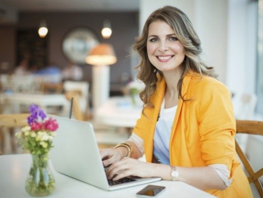 Woman in yellow business jacket typing on computer