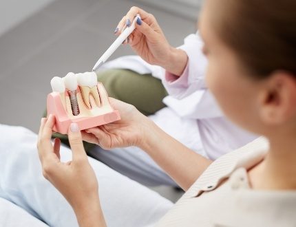 Dentist showing model of dental implant to a patient