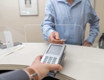 Man handing payment card to person behind desk