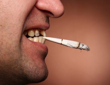 Man holding cigarette between his teeth