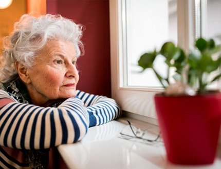 Sad older woman looking out her window