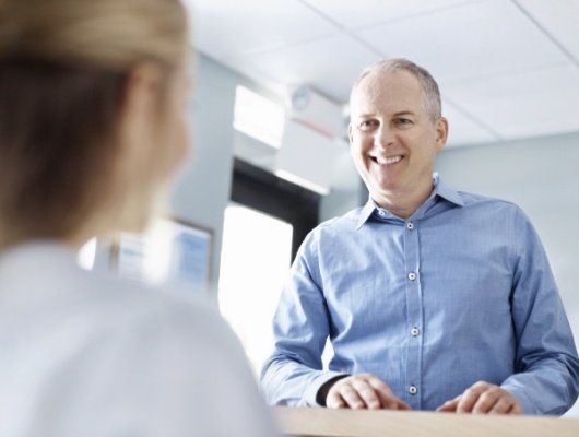 Man talking to dental team member at front desk