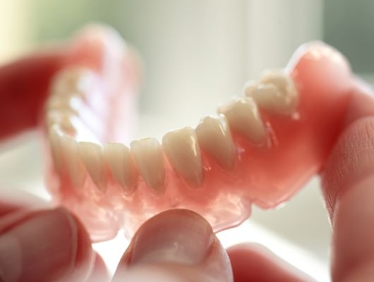 Person holding a full denture