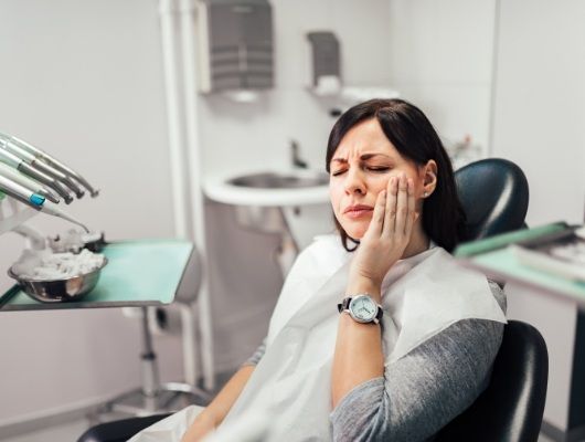 Dental patient holding her cheek in pain