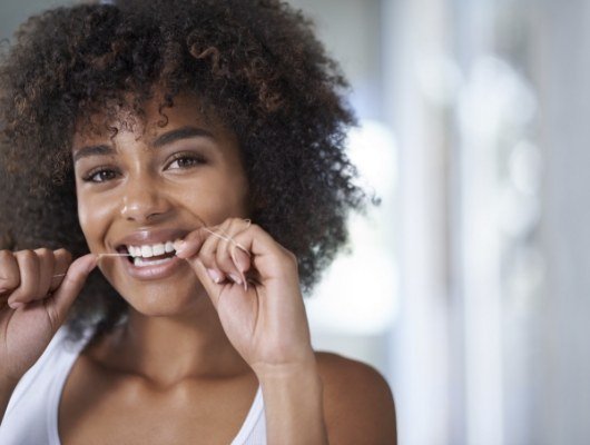 Woman smiling while flossing her teeth