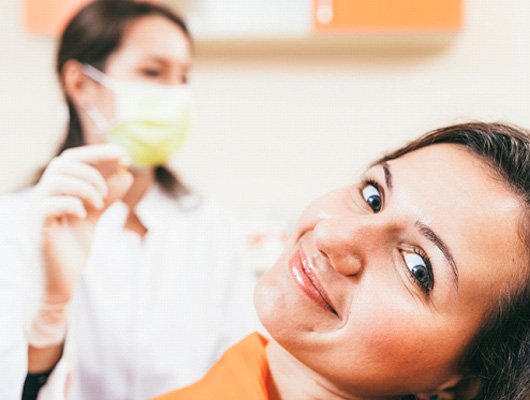 Dentist holding a smiling patient’s tooth