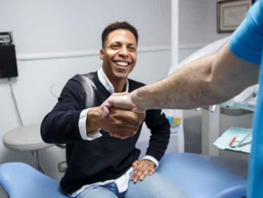Smiling man shaking hands with his dentist