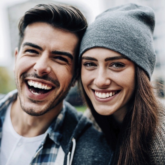 Man and woman grinning outdoors after gum disease treatment in Denton