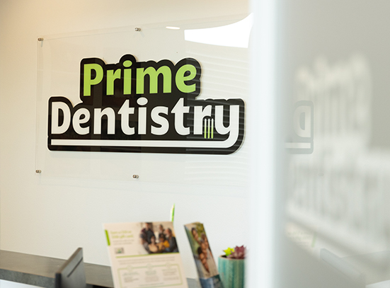Prime Dentistry sign on wall behind front desk of dental office in Denton
