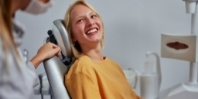 Woman in yellow sweater grinning at her dentist