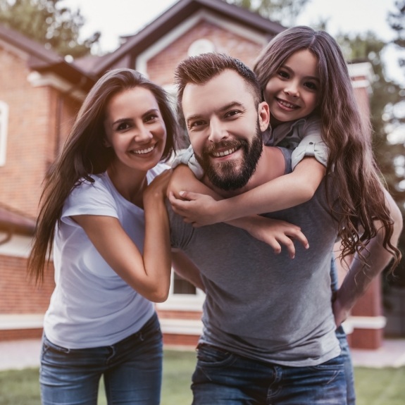 Family of three smiling in their front yard