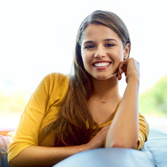 Young woman in yellow blouse smiling with Invisalign in Denton