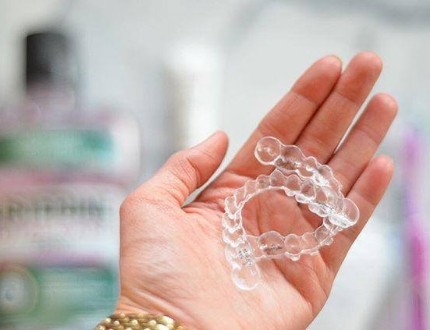 Person holding two clear aligners in their hand