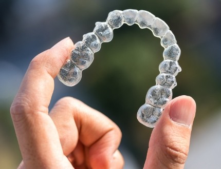 Close up of hand holding Invisalign aligner