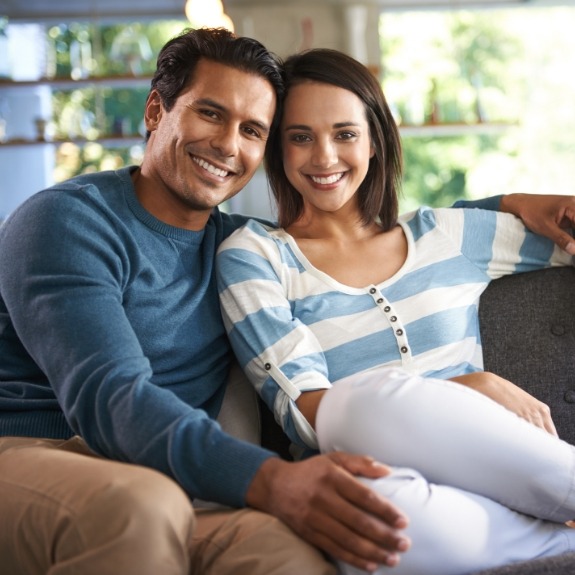 Man and woman smiling on couch with metal free dental restorations