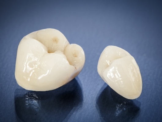 Two dental crowns against dark blue background