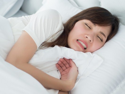 WOman cringing while lying in bed