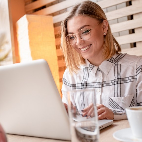 Woman smiling while typing on laptop