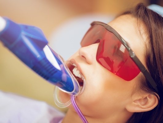 Young woman getting fluoride treatment in dental chair