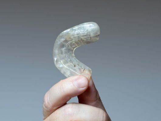 Hand holding a white nightguard for bruxism