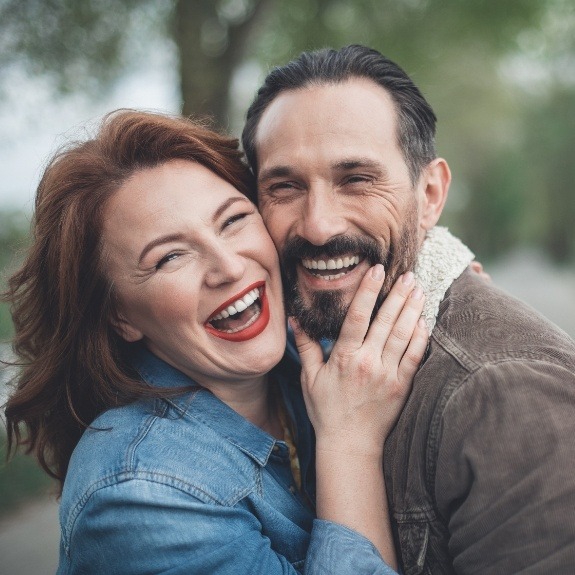 Older man and woman laughing after restorative dentistry in Denton