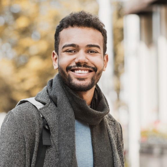 Man with scarf smiling after root canal treatment in Denton