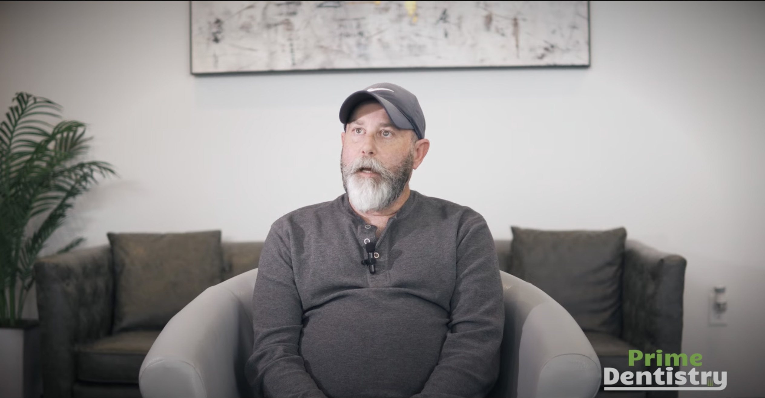 Man with baseball cap sitting in armchair in dental office