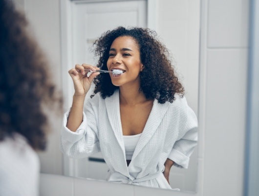 Woman smiling while brushing her teeth