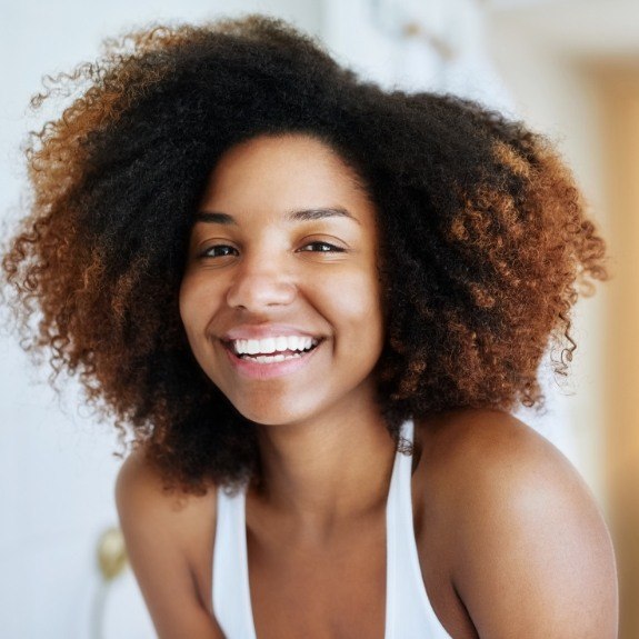 Young woman in white tank top smiling with veneers in Denton