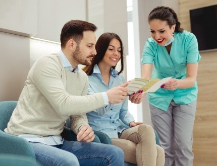 Dental team member showing pamphlet to two patients