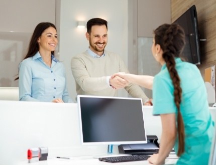 Dental team member shaking hands with a patient at front desk