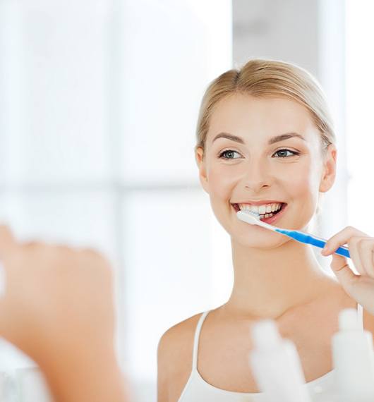 Woman looking in mirror to brush her teeth