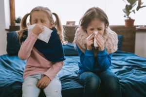 Two little girls sneezing during cold and flu season