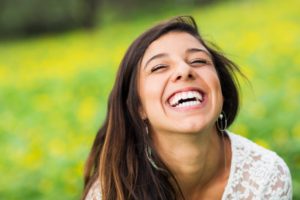 Woman smiling outside while protecting her lips from the sun