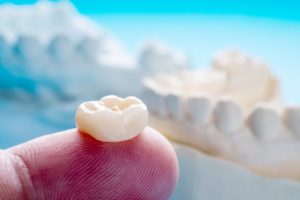 dentist holding a dental crown on their finger 