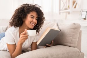 A woman smiling and drinking a cup of coffee