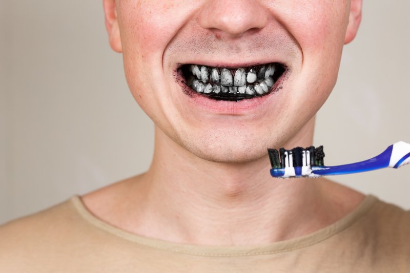 Man brushing his teeth with charcoal toothpaste