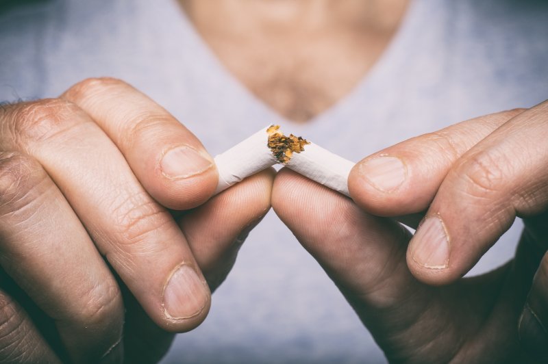 closeup of man breaking cigarette in half