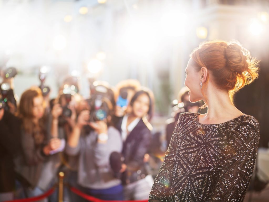 Celebrity smiling at cameras on red carpet