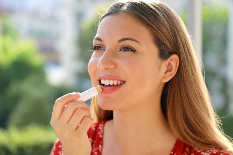 woman putting on lip balm