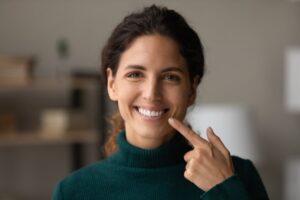 Woman smiling and pointing to her teeth.