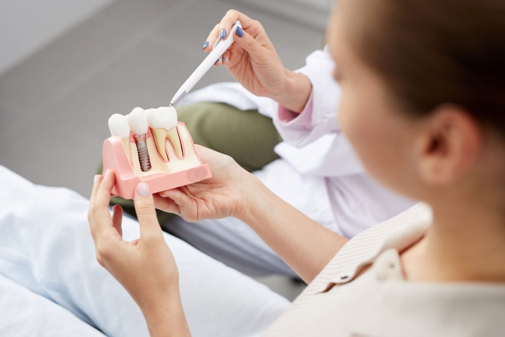 Woman holding sample dental implant that dentist is pointing to