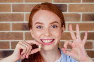 Woman smiling while holding a tooth model